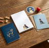 Notebooks and stationery items with dog illustrations on a wooden surface